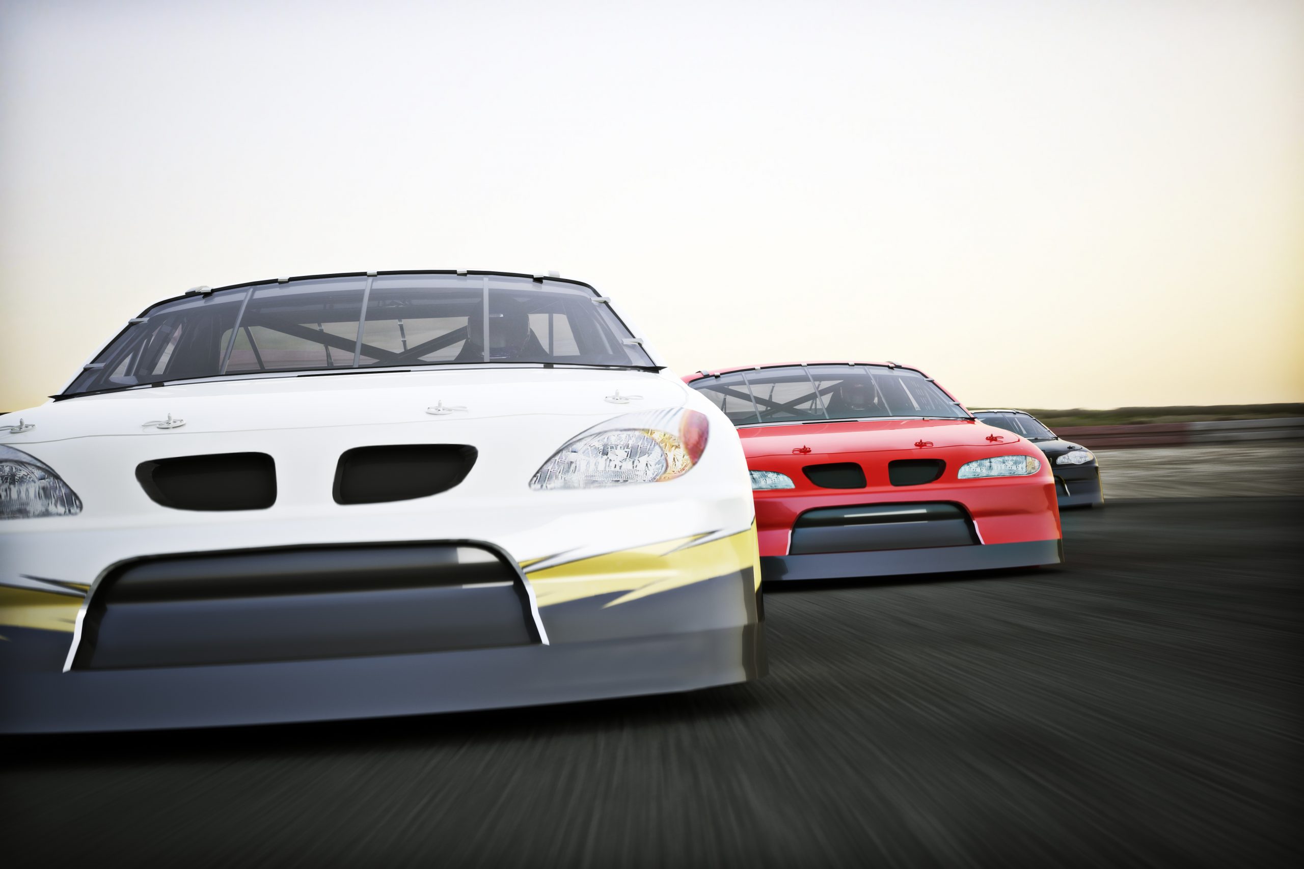 Front view of auto racing race cars racing on a track with motio
